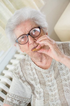 Téléchargez les photos : Portrait de femme âgée mangeant des biscuits. - en image libre de droit