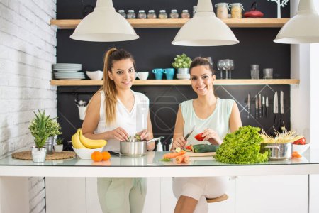 Téléchargez les photos : Sœurs jumelles préparant le repas dans la cuisine - en image libre de droit