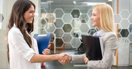 Photo for Beautiful business women shaking hands in office - Royalty Free Image