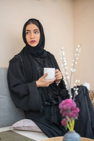 Téléchargez les photos : Belle jeune femme musulmane buvant du café à la maison. - en image libre de droit