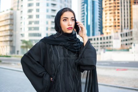 Téléchargez les photos : Belle femme arabe parlant sur son téléphone portable dans la rue - en image libre de droit
