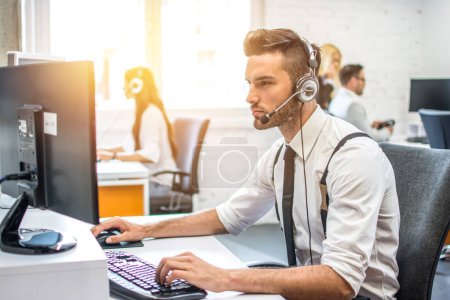 Téléchargez les photos : Opérateur de support technique travaillant sur ordinateur dans le centre d'appels - en image libre de droit