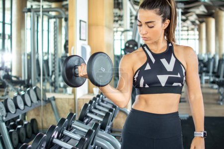Photo for Beautiful attractive young fit sporty woman lifting weights in the gym - Royalty Free Image