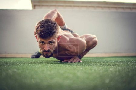 Téléchargez les photos : Musclé homme faire push-ups sur une main à l'extérieur - en image libre de droit