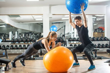 Téléchargez les photos : Jeune femme et homme séance d'entraînement avec des balles de fitness dans la salle de gym. - en image libre de droit
