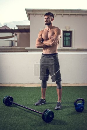 Foto de Longitud completa del hombre sin camisa atlética preparándose para el entrenamiento con pesas al aire libre. - Imagen libre de derechos