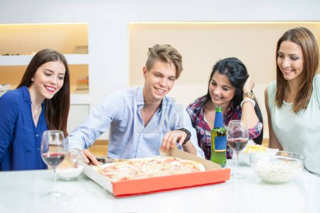 Photo for Smiling friends eating pizza at home - Royalty Free Image