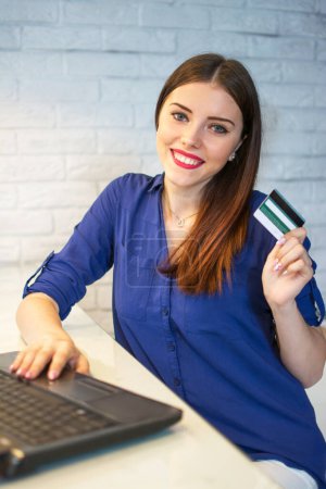 Retrato de la mujer sonriente de compras en línea con tarjeta de crédito y portátil