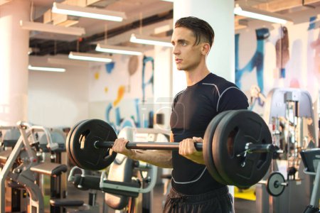 Photo for Young strong man working out with barbells in gym. - Royalty Free Image