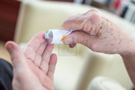 Photo for Close up of senior womans wrinkled hands applying cream at home. - Royalty Free Image