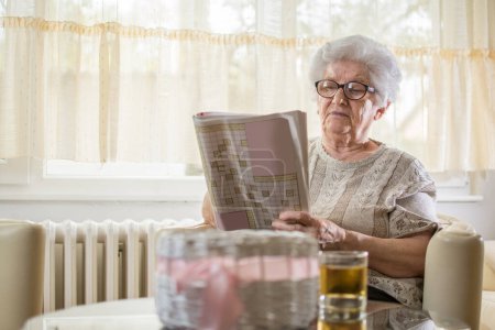 Photo for Concentrated senior woman doing some crossword at home. - Royalty Free Image