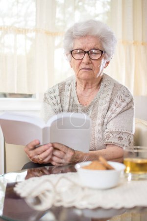 Photo for Senior woman reading book at home. - Royalty Free Image