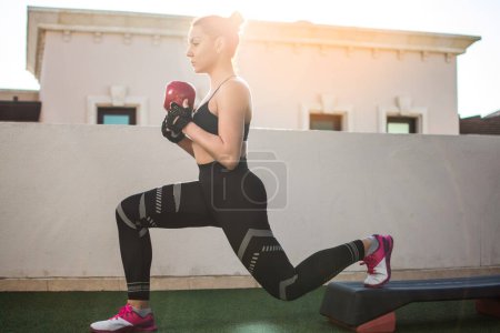 Photo for Fit sportswoman exercising with kettle bell on fitness stepper outdoors. - Royalty Free Image
