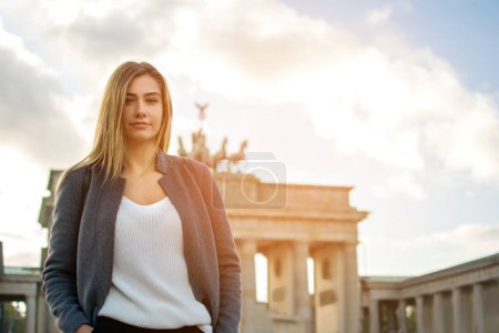 Téléchargez les photos : Portrait d'une belle jeune femme debout devant la porte de Brandebourg à Berlin, Allemagne. - en image libre de droit