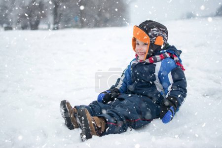 Photo for Little boy sitting in snow - Royalty Free Image