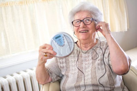Téléchargez les photos : Femme âgée joyeuse écoutant de la musique sur un lecteur CD. - en image libre de droit