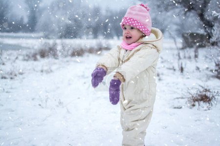 Photo for Cute little girl playing on snowy winter day in the park - Royalty Free Image