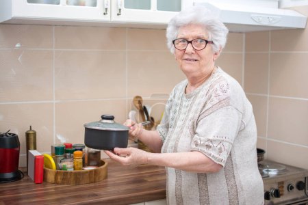 Photo for Portrait of senior woman holding cooking pan in the kitchen. - Royalty Free Image