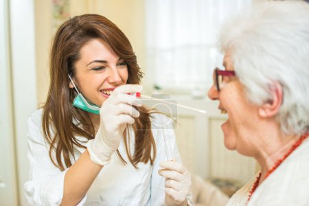 Médico o enfermero usando un hisopo para tomar una muestra de la garganta de un paciente mayor