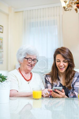 Photo for Granddaughter showing something on phone to her grandmother - Royalty Free Image