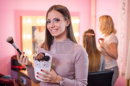 Photo for Smiling young woman holding brushes in beauty salon. - Royalty Free Image