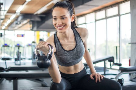 Photo for Sportswoman lifting kettle bell at gym - Royalty Free Image