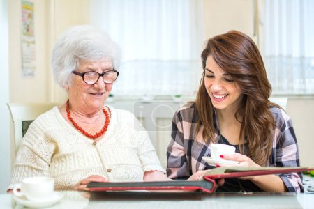 Photo for Grandmother and granddaughter looking at photo album together - Royalty Free Image