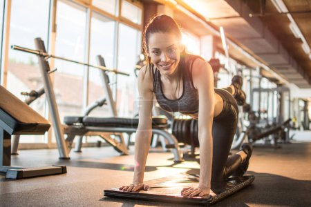 Téléchargez les photos : Jeune femme en forme faisant des exercices pour les jambes sur tapis à la salle de gym - en image libre de droit