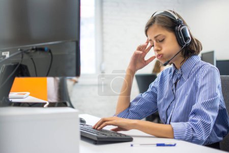 Foto de Operadora de centro de llamadas cansada mujer en el lugar de trabajo en la oficina. - Imagen libre de derechos