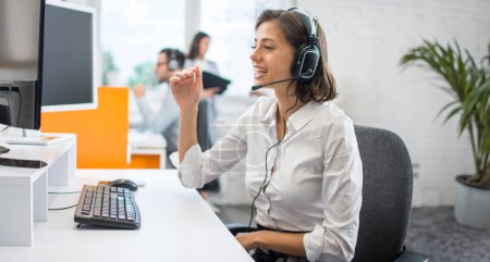 Téléchargez les photos : Portrait d'une femme d'affaires souriante écoutant le client via un casque et répondant aux appels des clients dans le bureau du centre d'appels. - en image libre de droit