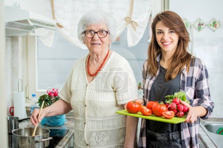 Foto de Sonriente abuela con nieta cocinando en la cocina - Imagen libre de derechos