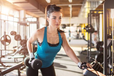 Téléchargez les photos : Fitness femme soulevant des poids dans la salle de gym - en image libre de droit