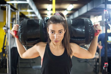 Foto de Joven mujer de fitness llevando en bolsa de fitness en sus hombros en el gimnasio. - Imagen libre de derechos