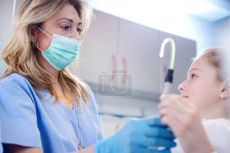 Foto de Niña tomando un tubo de succión del dentista y preparándose para el chequeo dental - Imagen libre de derechos