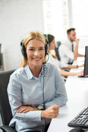 Smiling customer support operator woman at work. Young female employee working with a headset