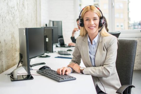 Téléchargez les photos : Jeune blonde opérateur de centre d'appels femme sur le lieu de travail - en image libre de droit