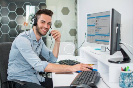 Foto de Operador masculino del centro de llamadas que trabaja en la computadora en oficina - Imagen libre de derechos