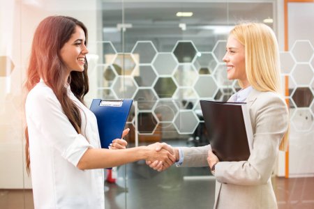 Photo for Two beautiful businesswomen handshaking in office - Royalty Free Image