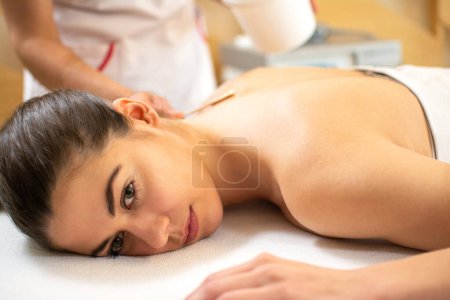Photo for Aesthetician applying a transparent gel with spatula before laser epilation on female client legs in beauty salon. - Royalty Free Image