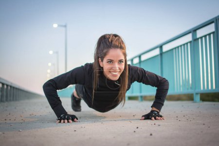 Photo for Below view of young woman doing push ups on road. - Royalty Free Image