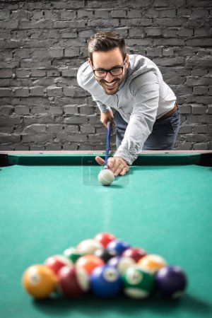 Téléchargez les photos : Homme d'affaires heureux jouant à un jeu de billard et se préparant à briser la pyramide des balles sur la table de billard - en image libre de droit