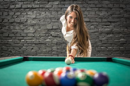 Foto de Feliz mujer de negocios jugando un juego de billar y preparándose para romper la pirámide de bolas en la mesa de billar. - Imagen libre de derechos