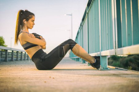 Photo for Fit young woman doing sit ups on a sidewalk - Royalty Free Image