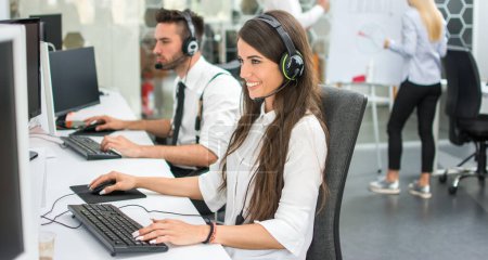 Photo for Cheerful customer support operators working in call center. Side view of smiling young business woman and business man talking with clients and solving problems on computers. - Royalty Free Image
