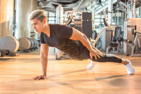 Foto de Musculoso hombre haciendo flexiones en una mano en el gimnasio - Imagen libre de derechos