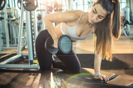 Téléchargez les photos : Fit femme faisant de l'exercice de levage de poids avec haltères dans la salle de gym. - en image libre de droit