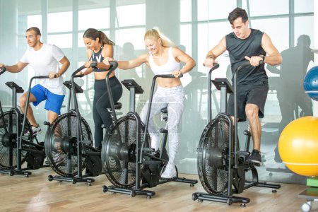 Gruppe sportlicher Menschen trainiert im Fitnessstudio auf einem Crosstrainer