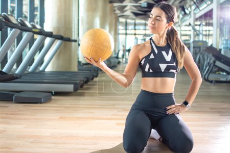 Foto de Hermosa joven deportista sosteniendo la pelota de fitness en el gimnasio - Imagen libre de derechos