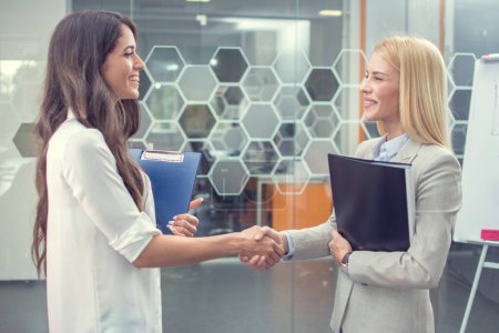 Photo for Young female business partners shaking hands after a business meeting in the office - Royalty Free Image
