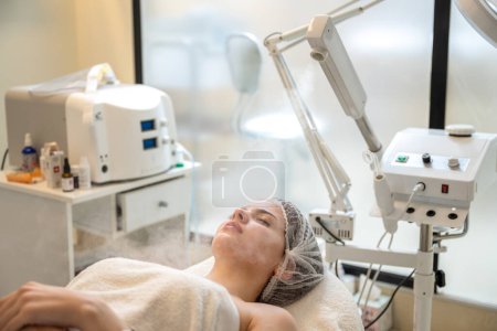Foto de Hermosa mujer en terapia de ozono con vapor facial en salón de belleza. - Imagen libre de derechos